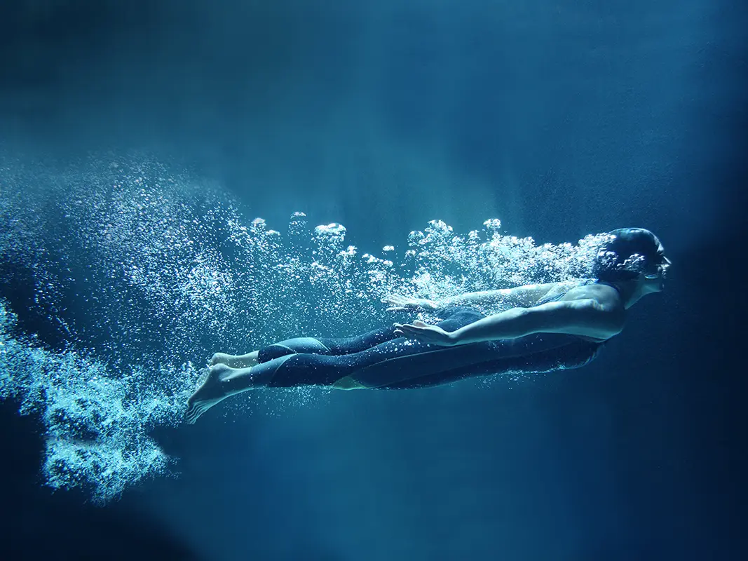 Woman swimming in a fiberglass swimming pool at night